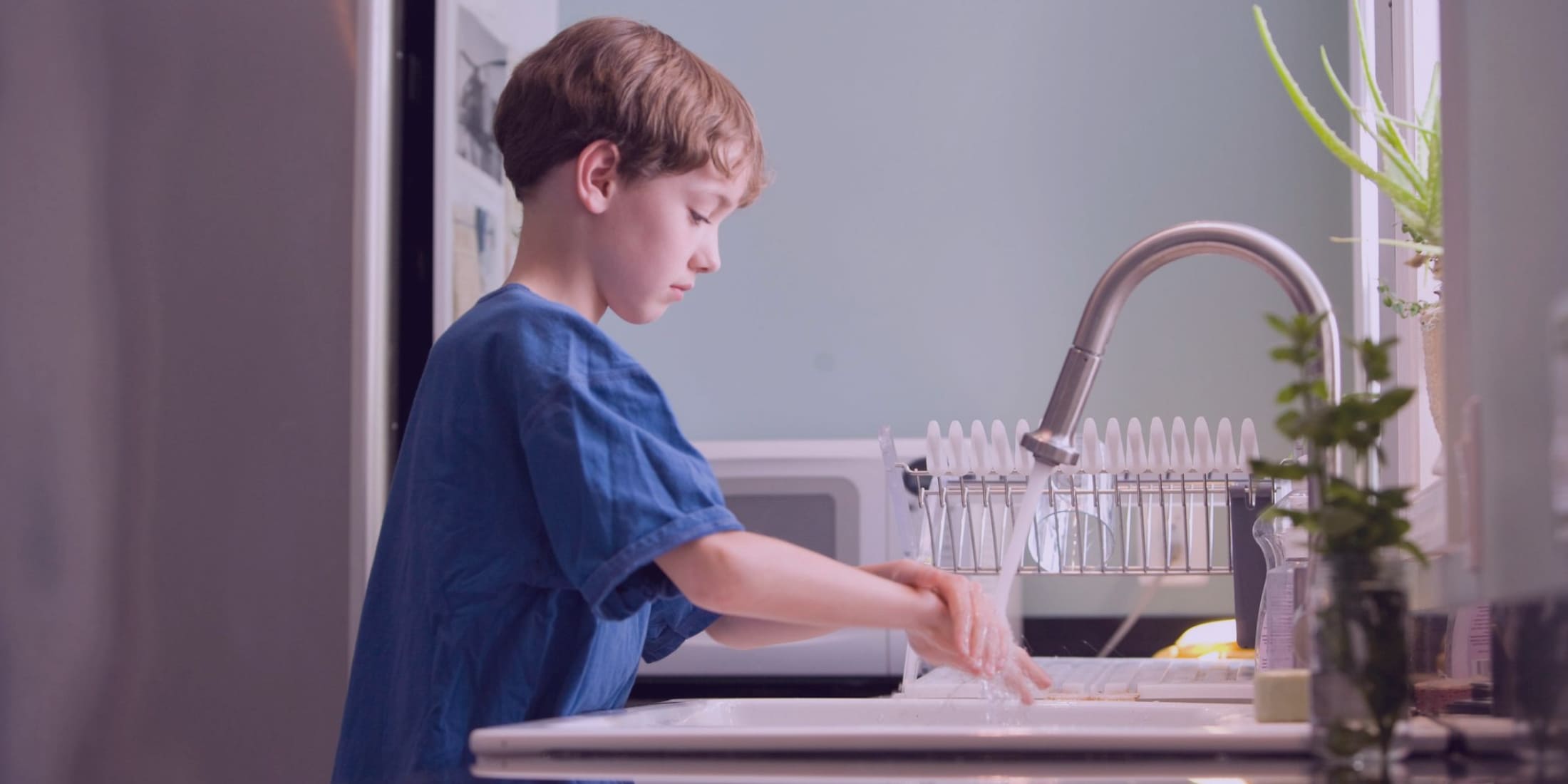 Мальчик в синей футболке моет руки с мылом. Его родители знают как укрепить ему иммунитет.