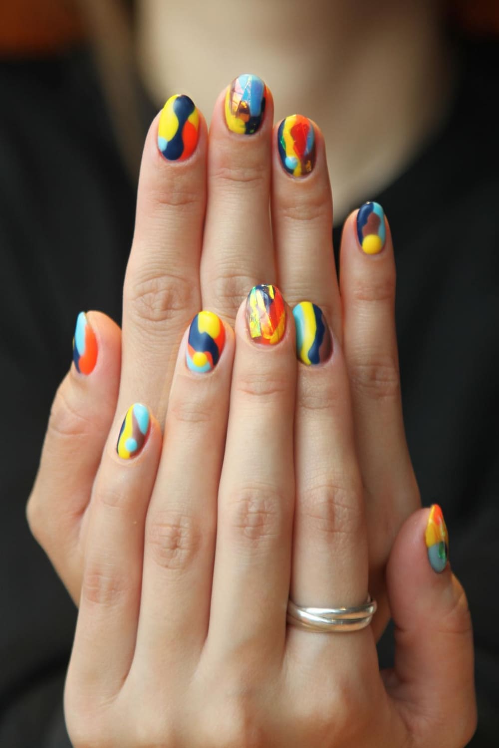 Две руки с укрепленными ногтями. На ногтях нанесен разноцветный лак.